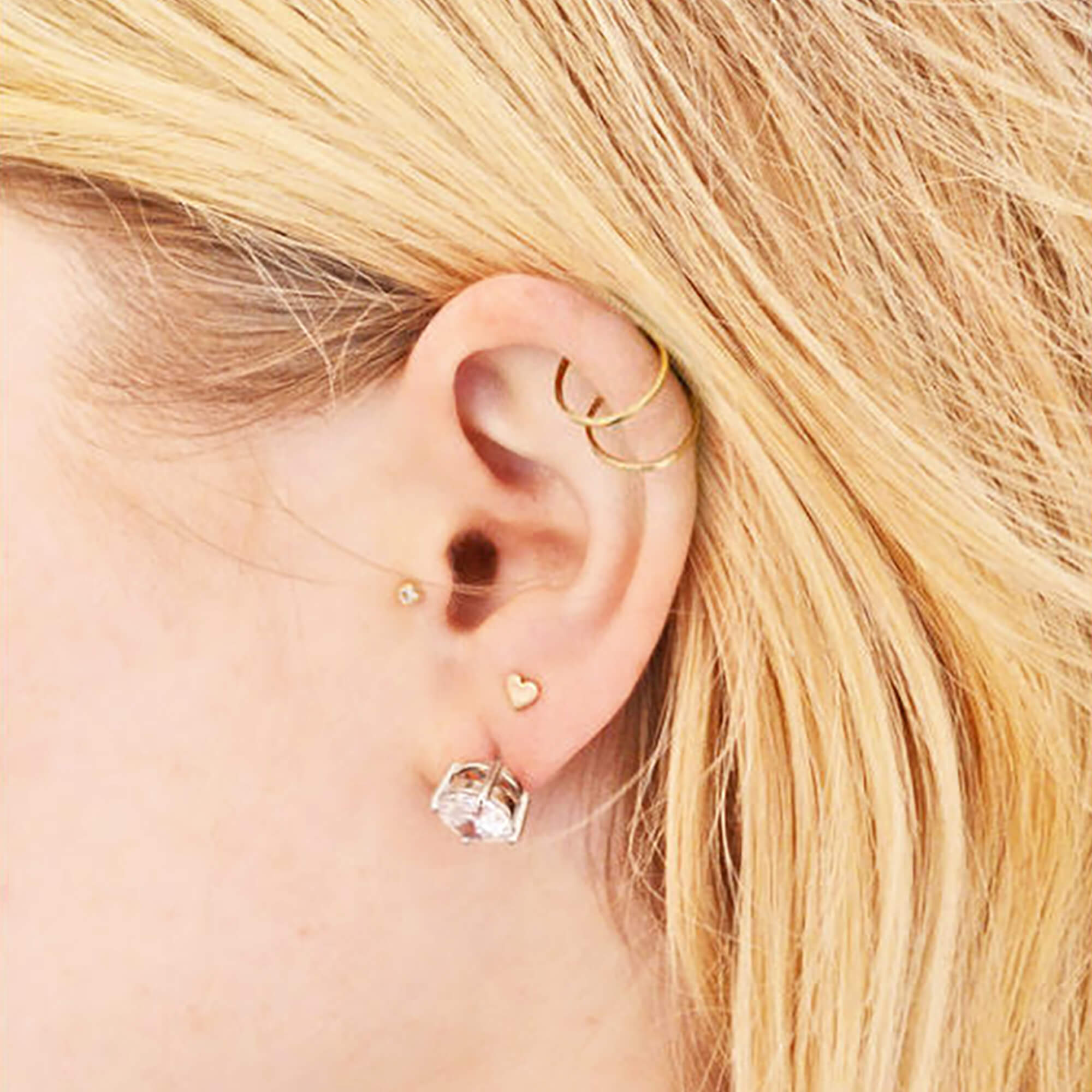 Before image of woman wearing heavy diamond stud earrings and earlobes visibly drooping and sagging