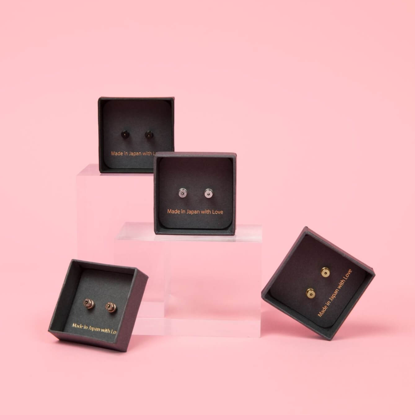 Chrysmela Catch without discs in yellow gold, platinum, rose gold and noir titanium against pink background