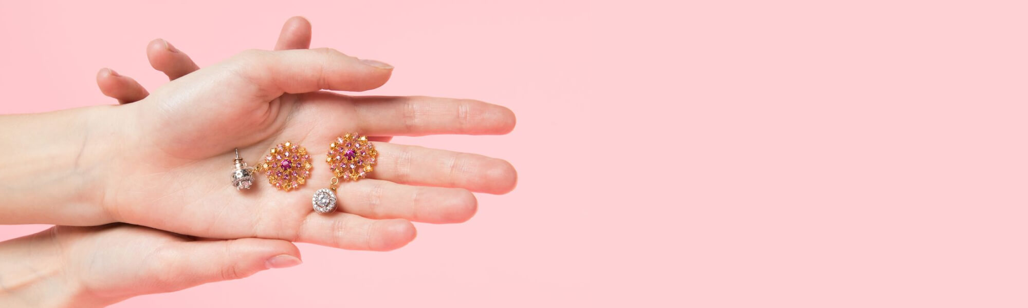 Hands holding Chrysmela Fireworks Earring Jackets against pink background